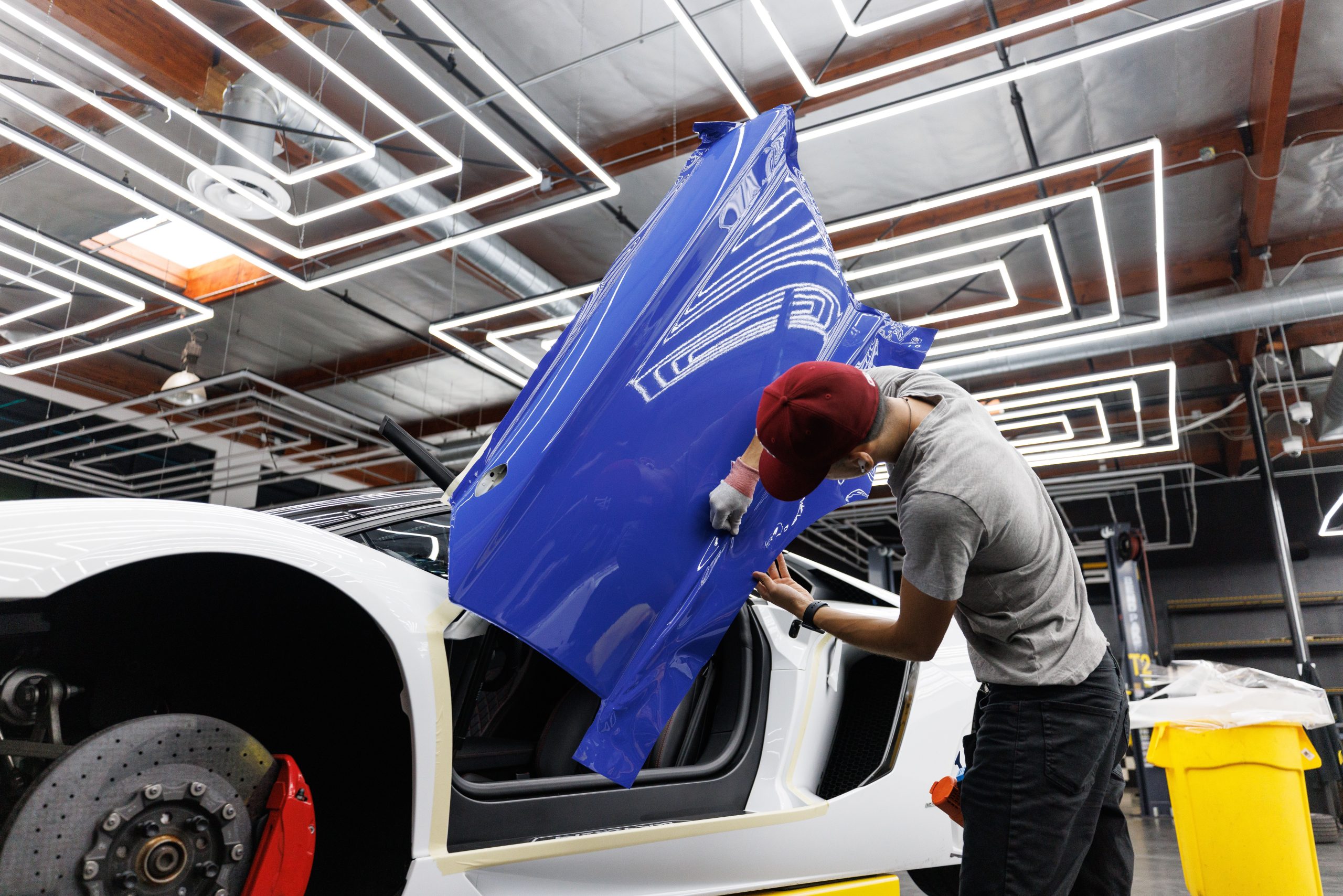 Vinyl wrap technician working on a car door panel, an example of a partial-wrap installation