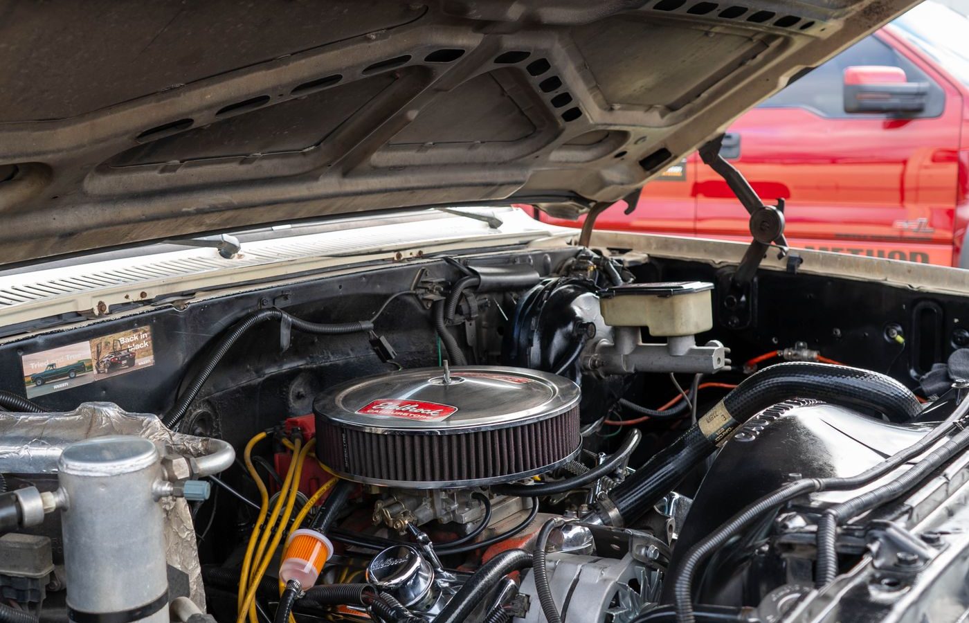 Close-up view into an engine bay with the hood raised, showing mounting points and accessories