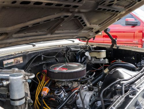 Close-up view into an engine bay with the hood raised, showing mounting points and accessories