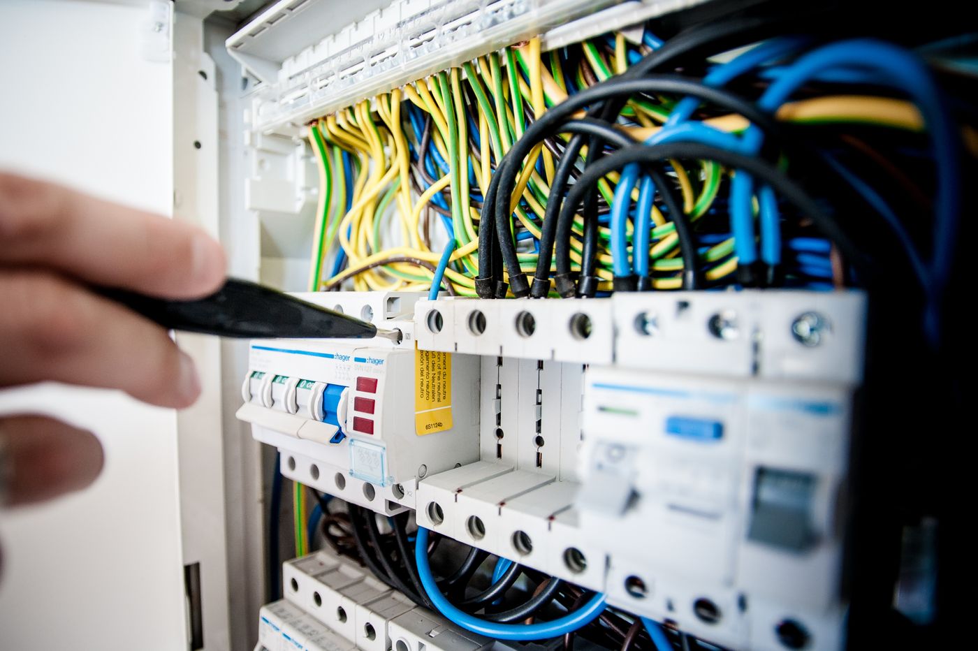 Electrician working inside an opened circuit breaker switchboard with colorful wires
