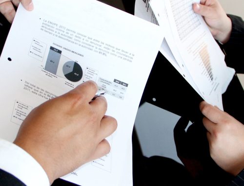 Person holding a stack of printed vehicle paperwork and documents