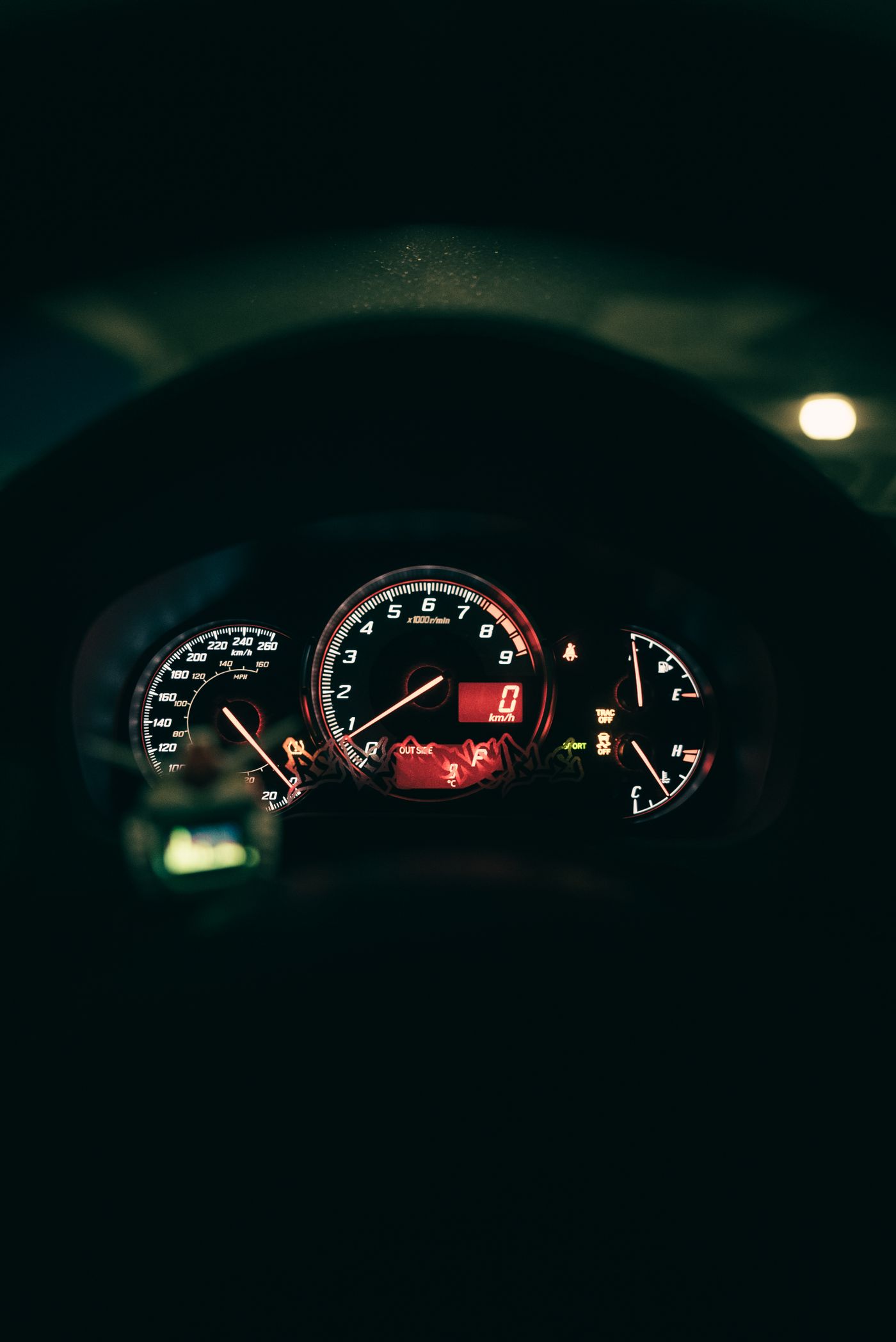Close-up of an illuminated car dashboard at night showing warning indicator lights