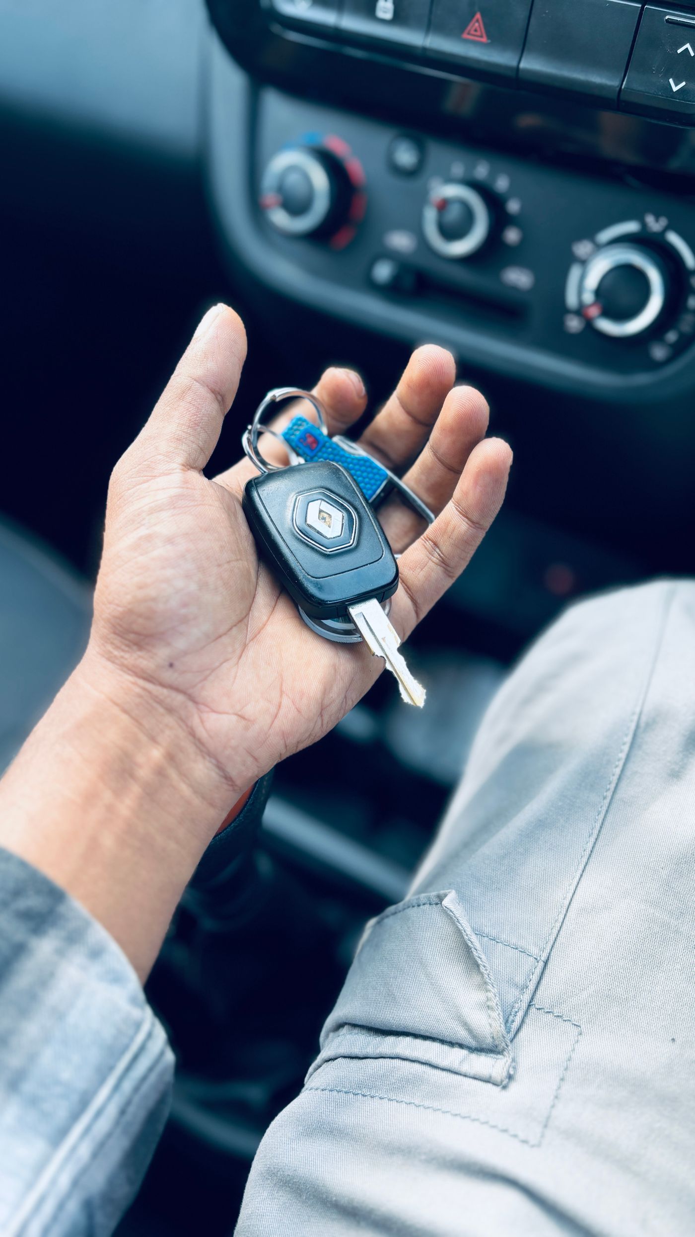 Close-up of a hand holding car keys inside a vehicle near the glove compartment