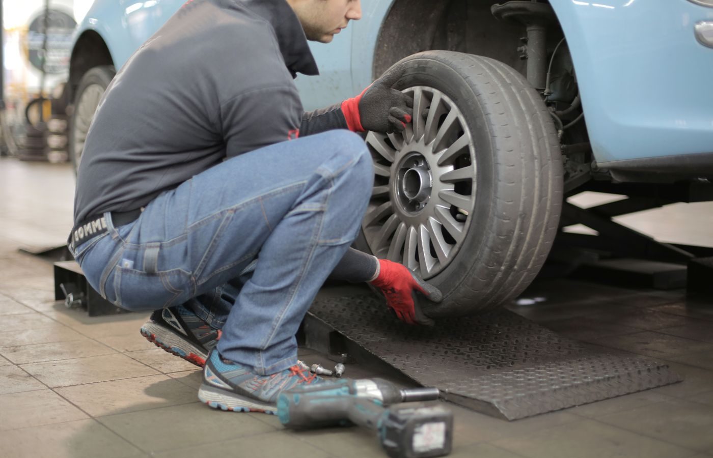 Person kneeling beside a car changing a wheel with a lug wrench