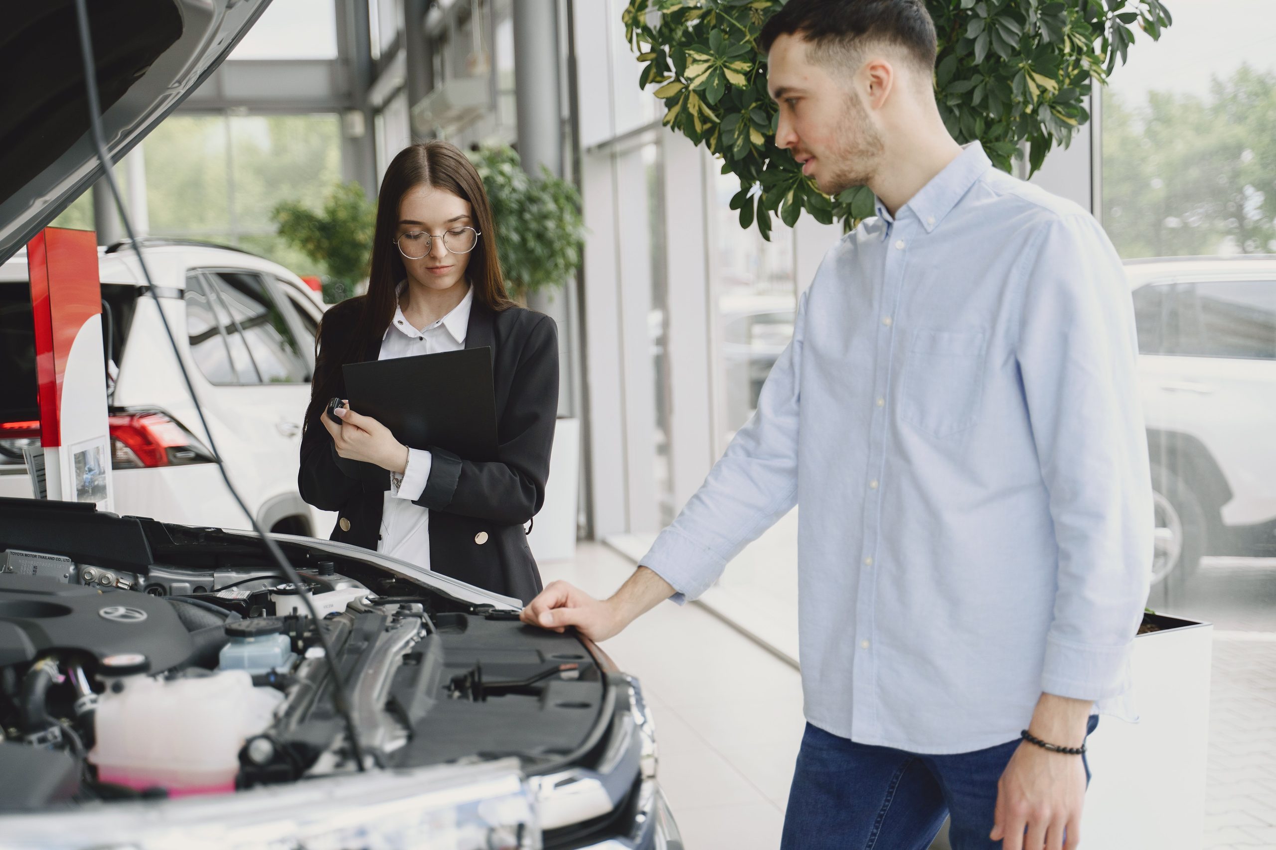 Man and woman examining a car engine during a service inspection