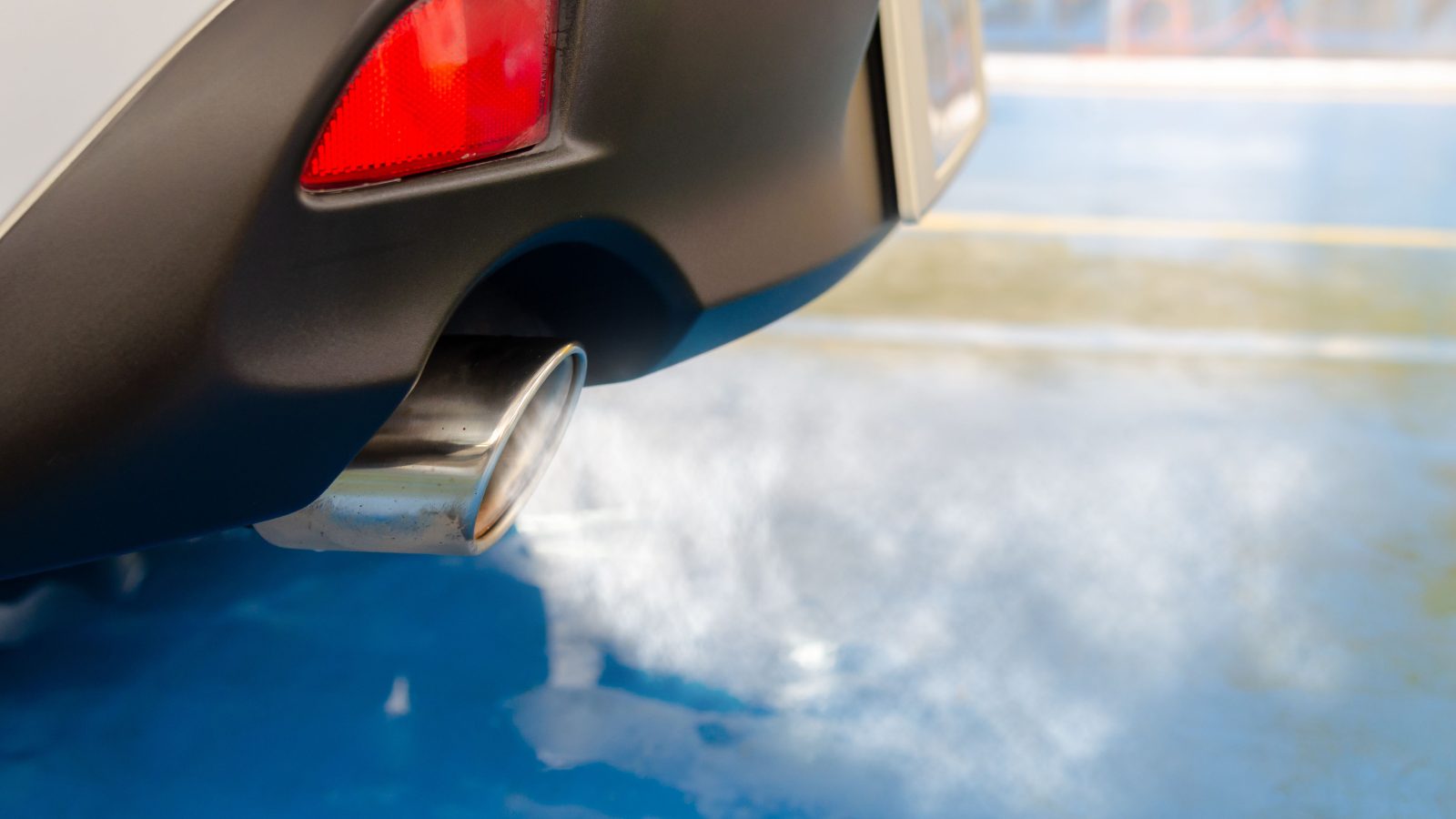 Close view of a car exhaust pipe emitting smoke