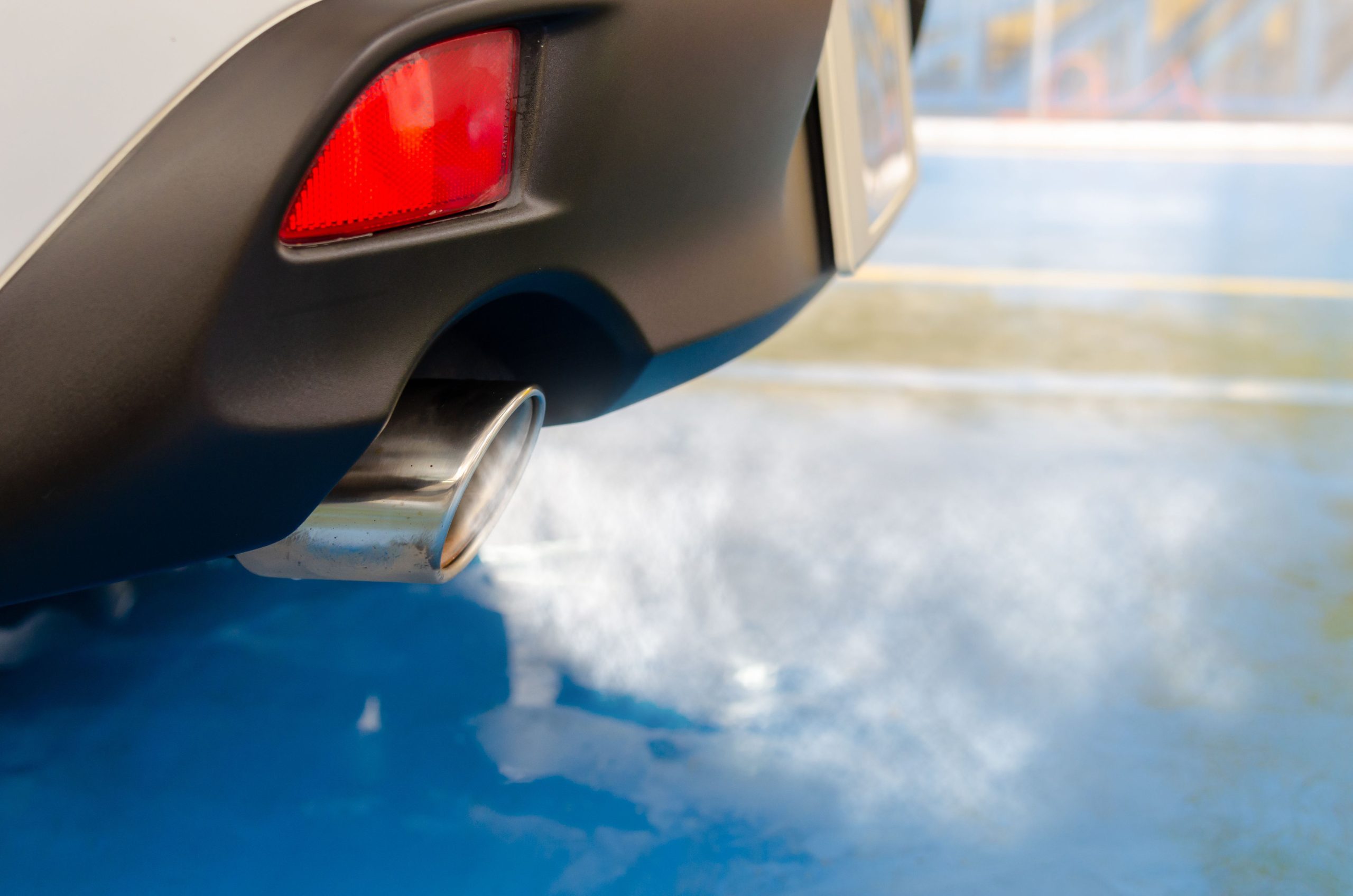 Close view of a car exhaust pipe emitting smoke