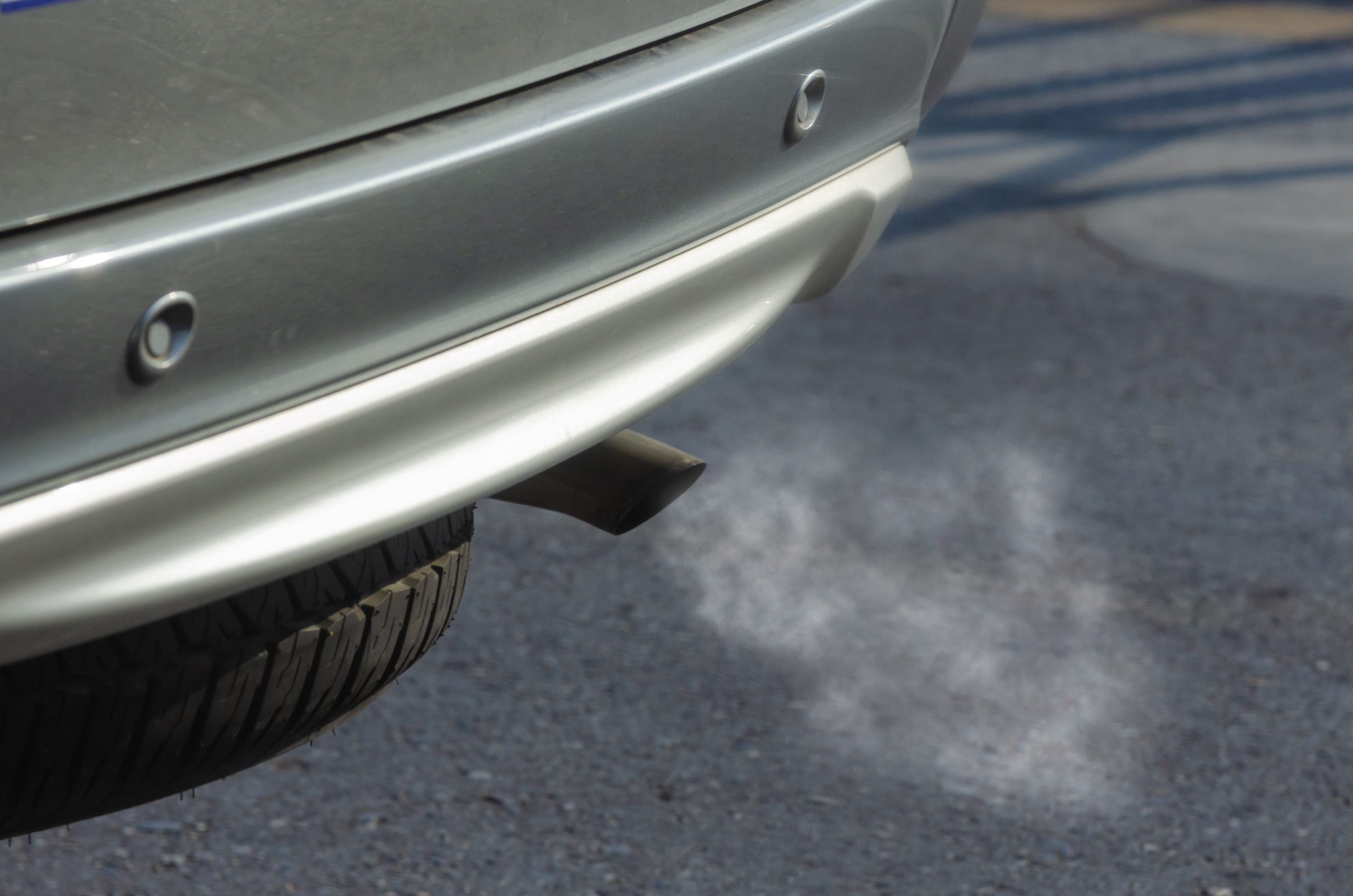 Silver car with a black exhaust pipe emitting smoke