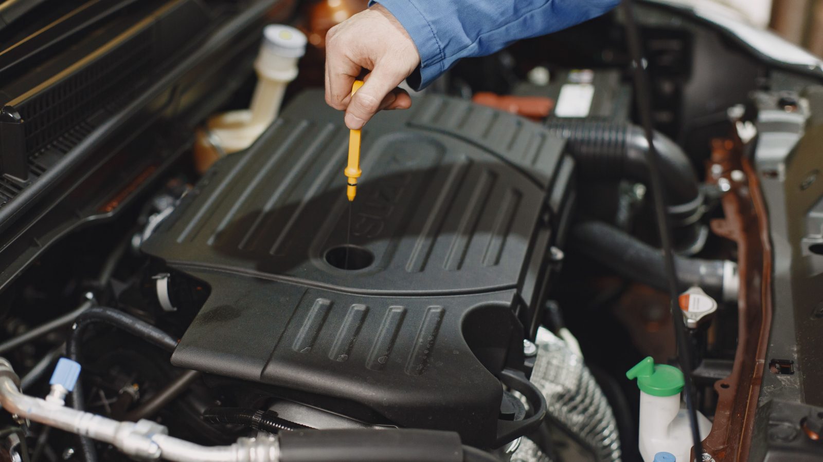 Person checking the oil of an engine with a dipstick