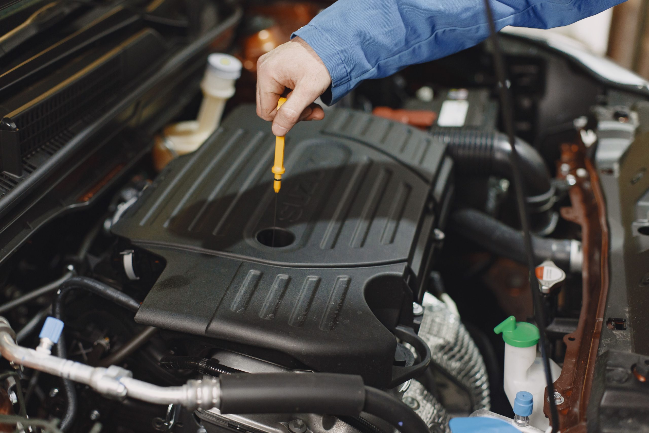 Person checking the oil of an engine with a dipstick