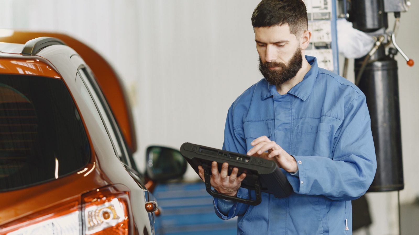 Mechanic in coveralls using an automotive diagnostic tool