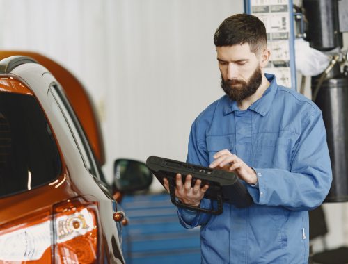 Mechanic in coveralls using an automotive diagnostic tool