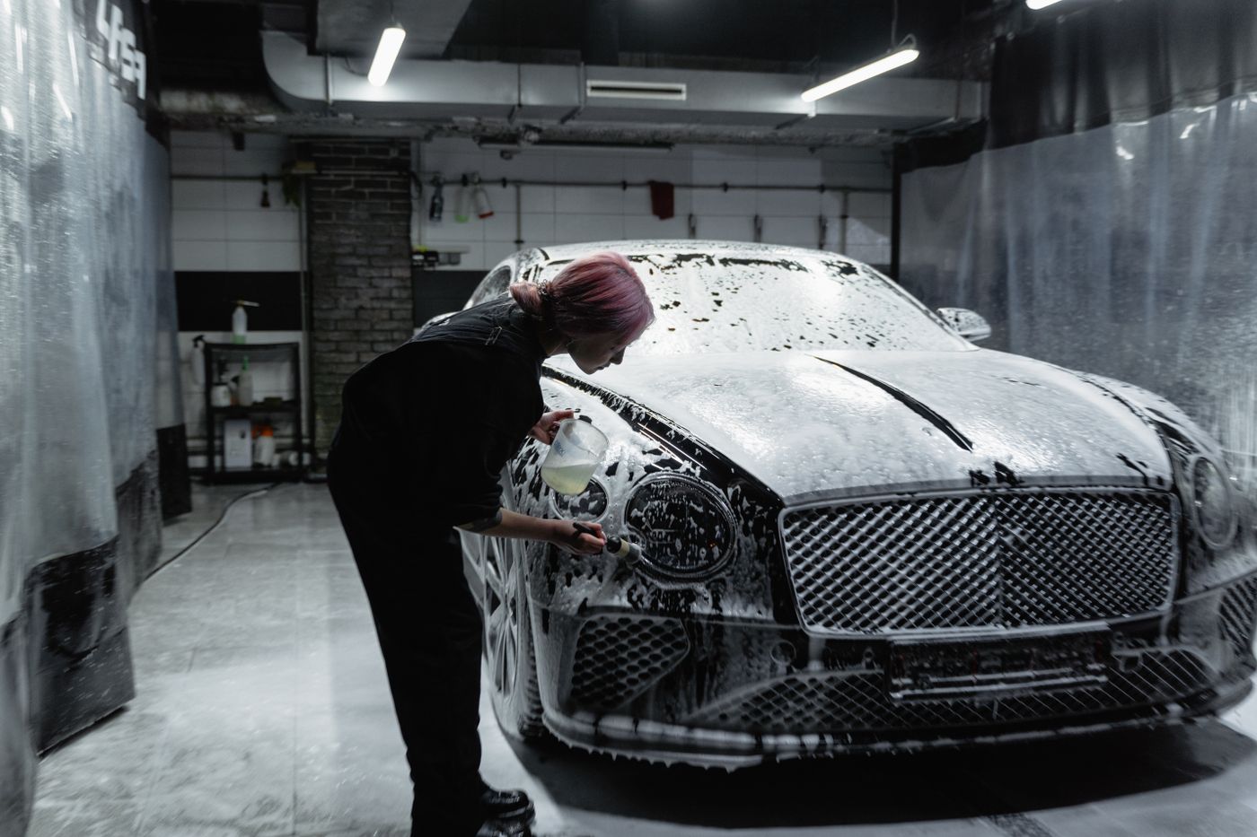 Thick foam soap covering the side of a car partway through a wash cycle