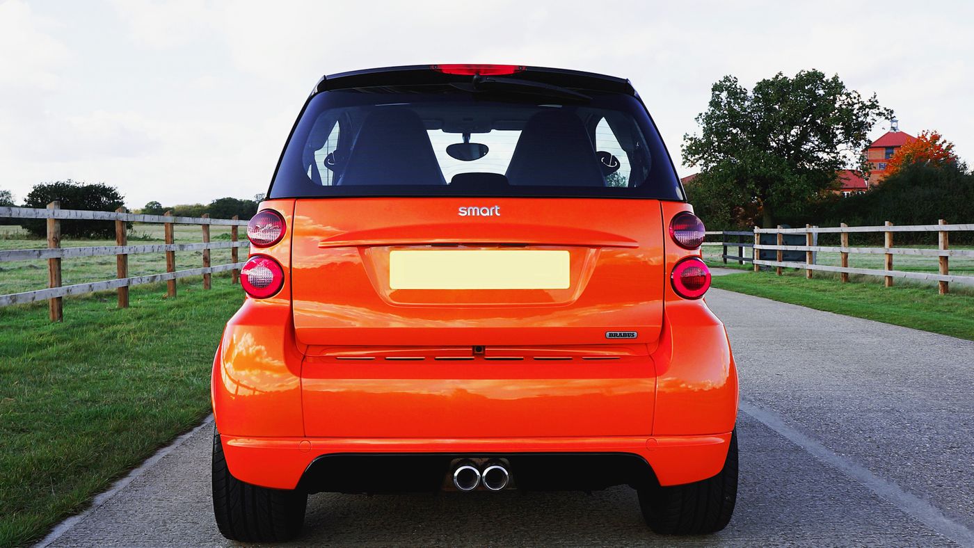 Orange Smart Fortwo driving on an open road, illustrating the car's compact footprint