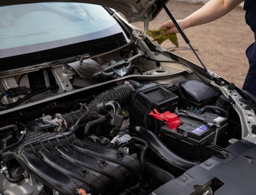 Mechanic inspecting the engine bay of a car with the hood open