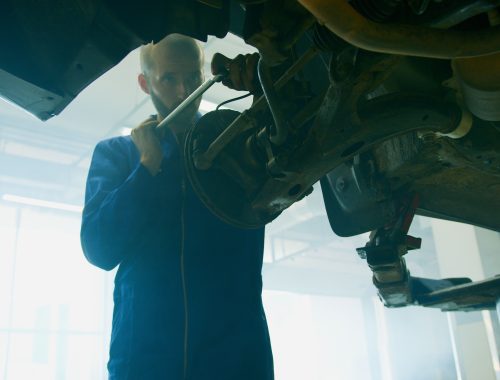 Mechanic holding a tool near an open car engine bay
