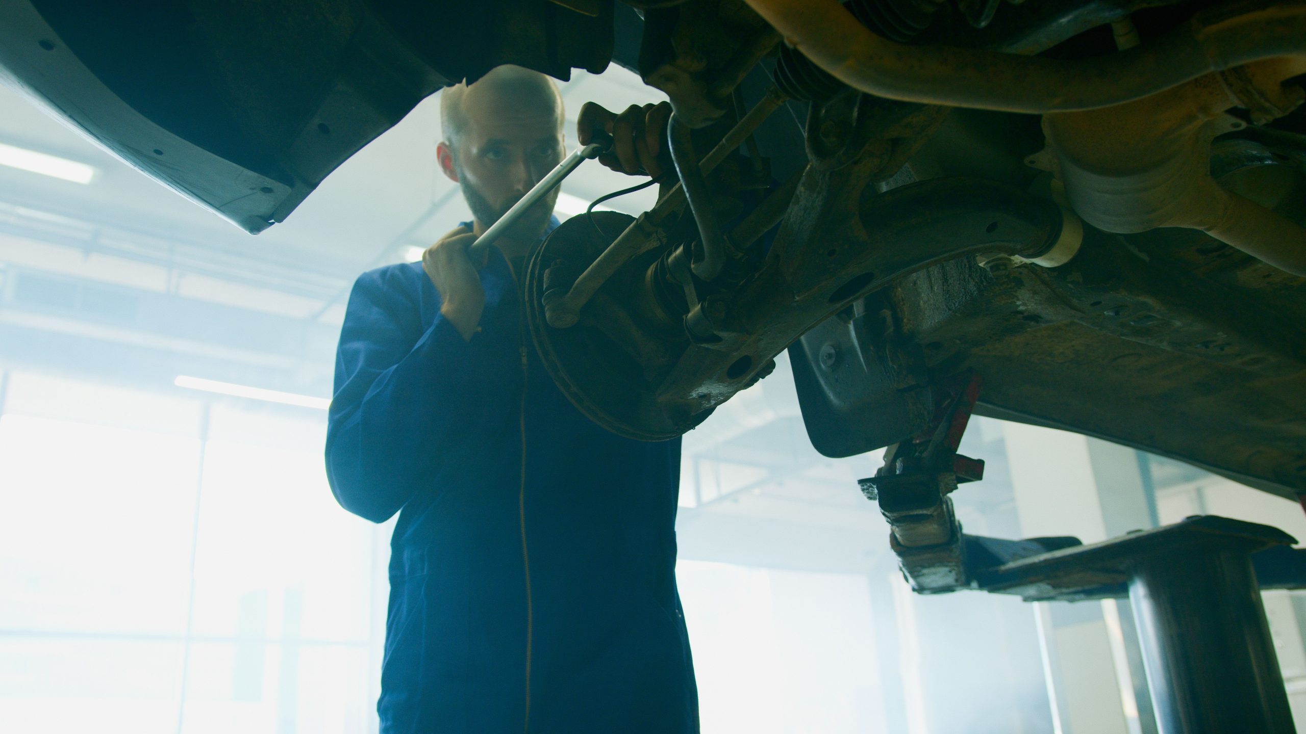 Mechanic holding a tool near an open car engine bay