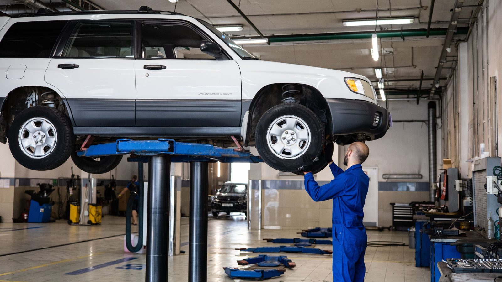Mechanic inspecting a vehicle lifted in an auto repair shop
