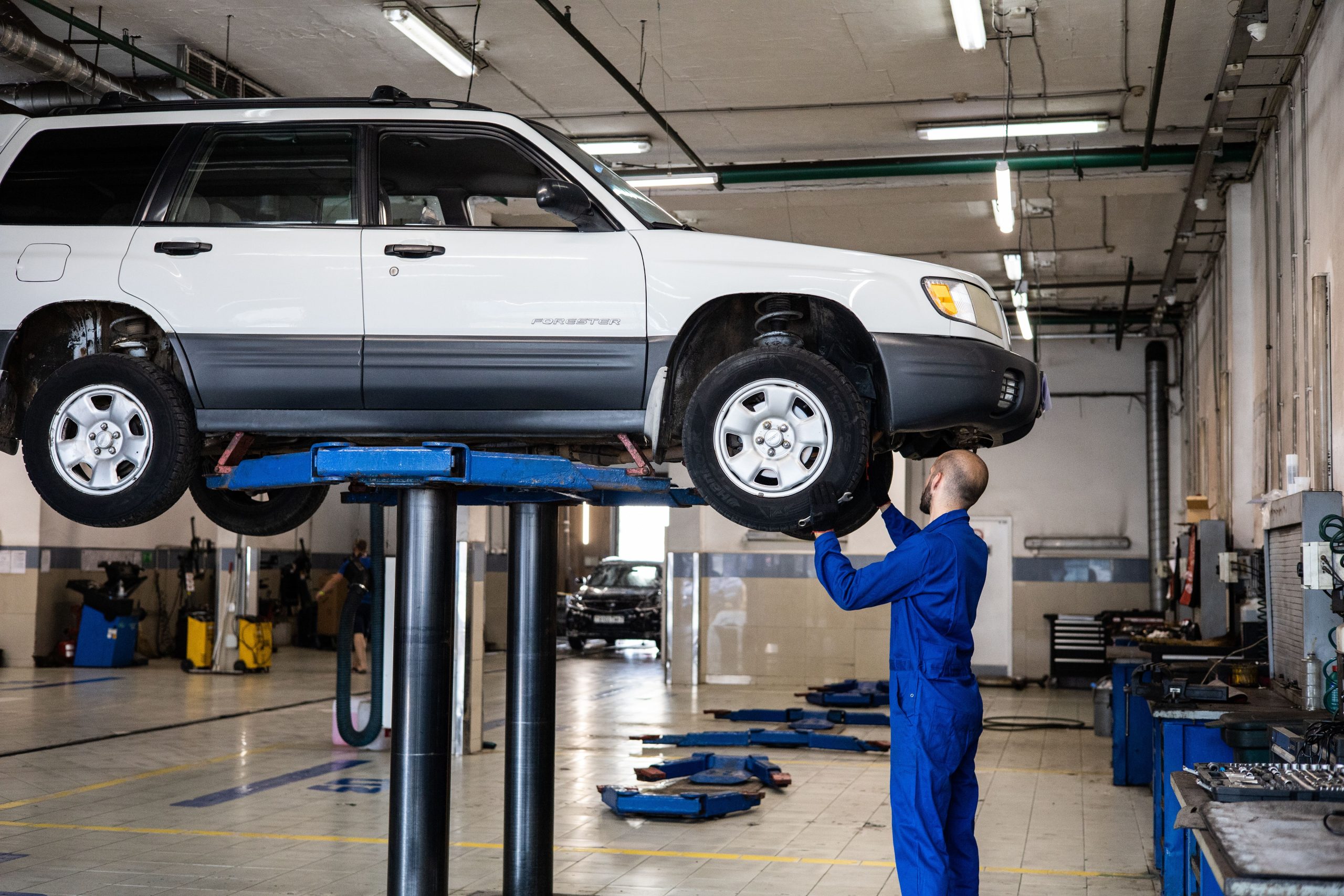 Mechanic inspecting a vehicle lifted in an auto repair shop
