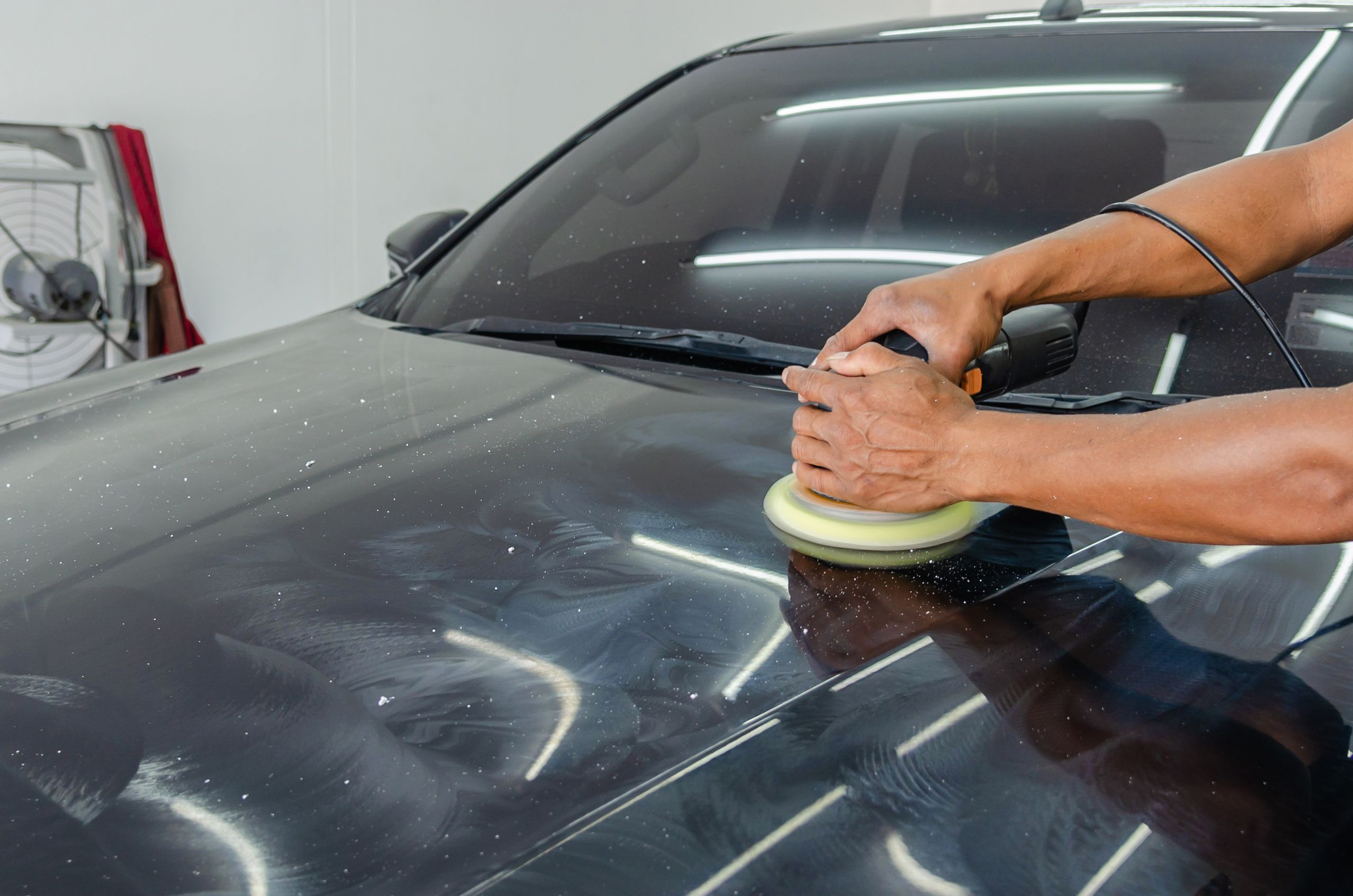 Person polishing a black car by hand