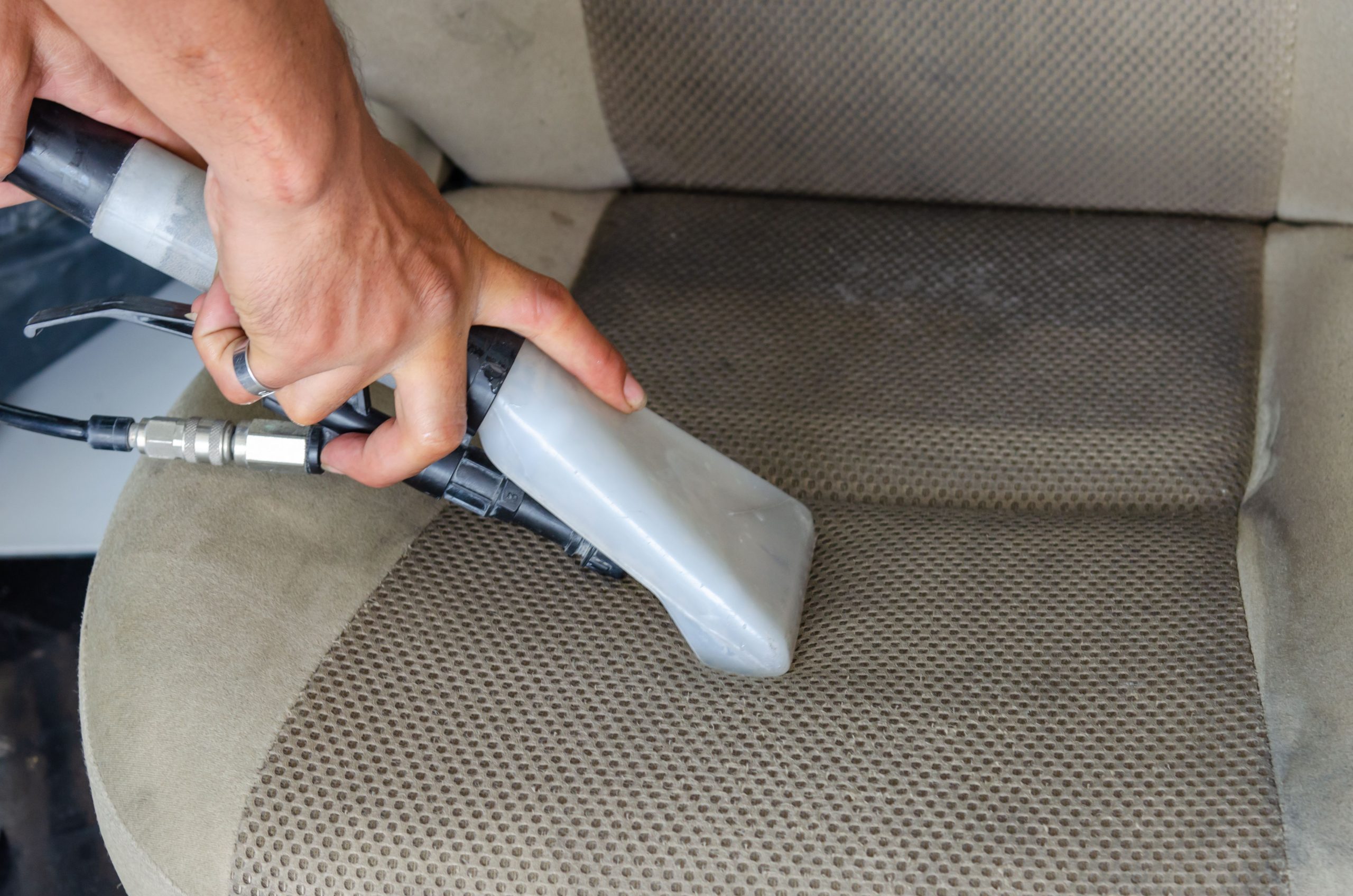 Car interior seat being deep cleaned with a vacuum