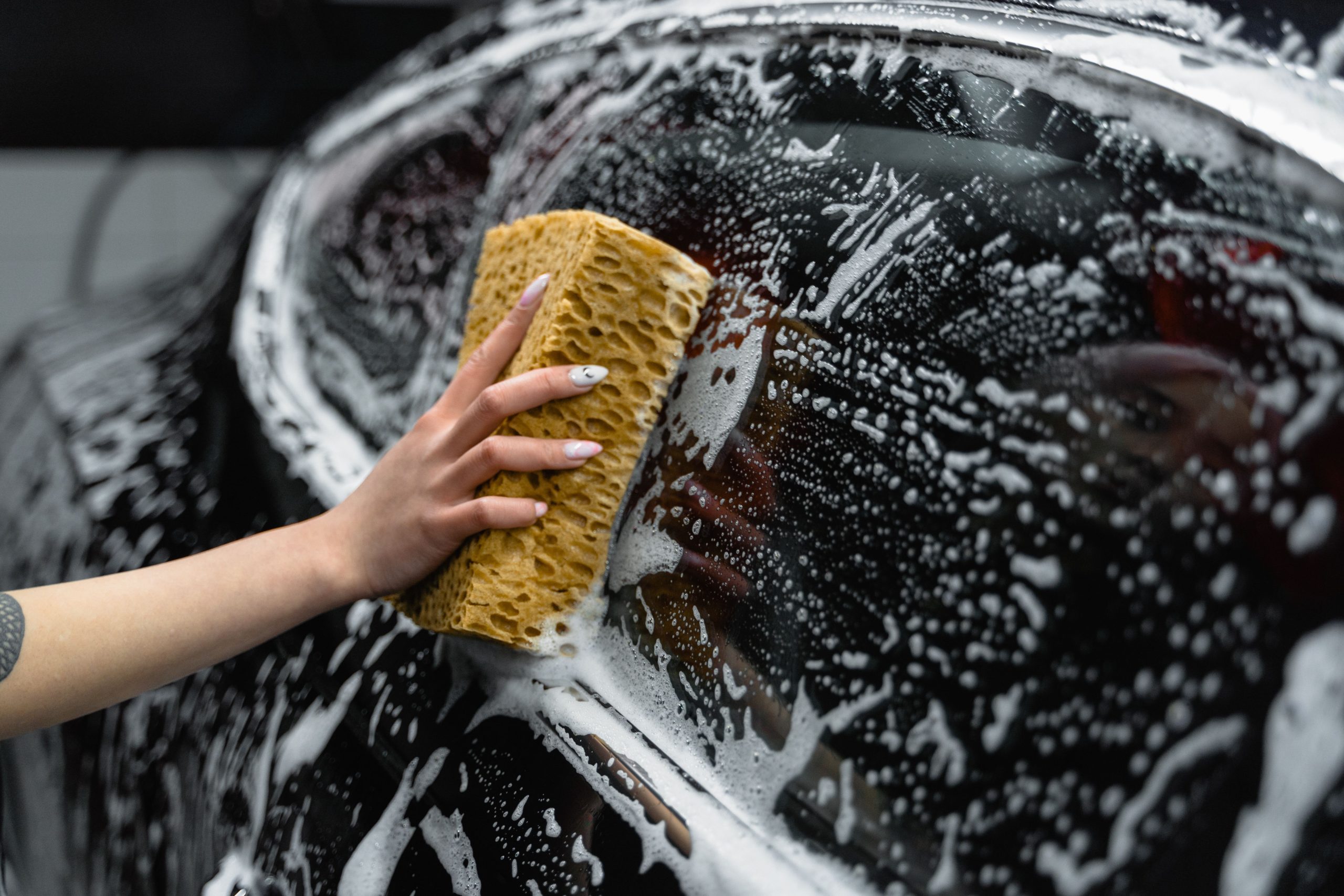Hand washing a car window with soap and foam