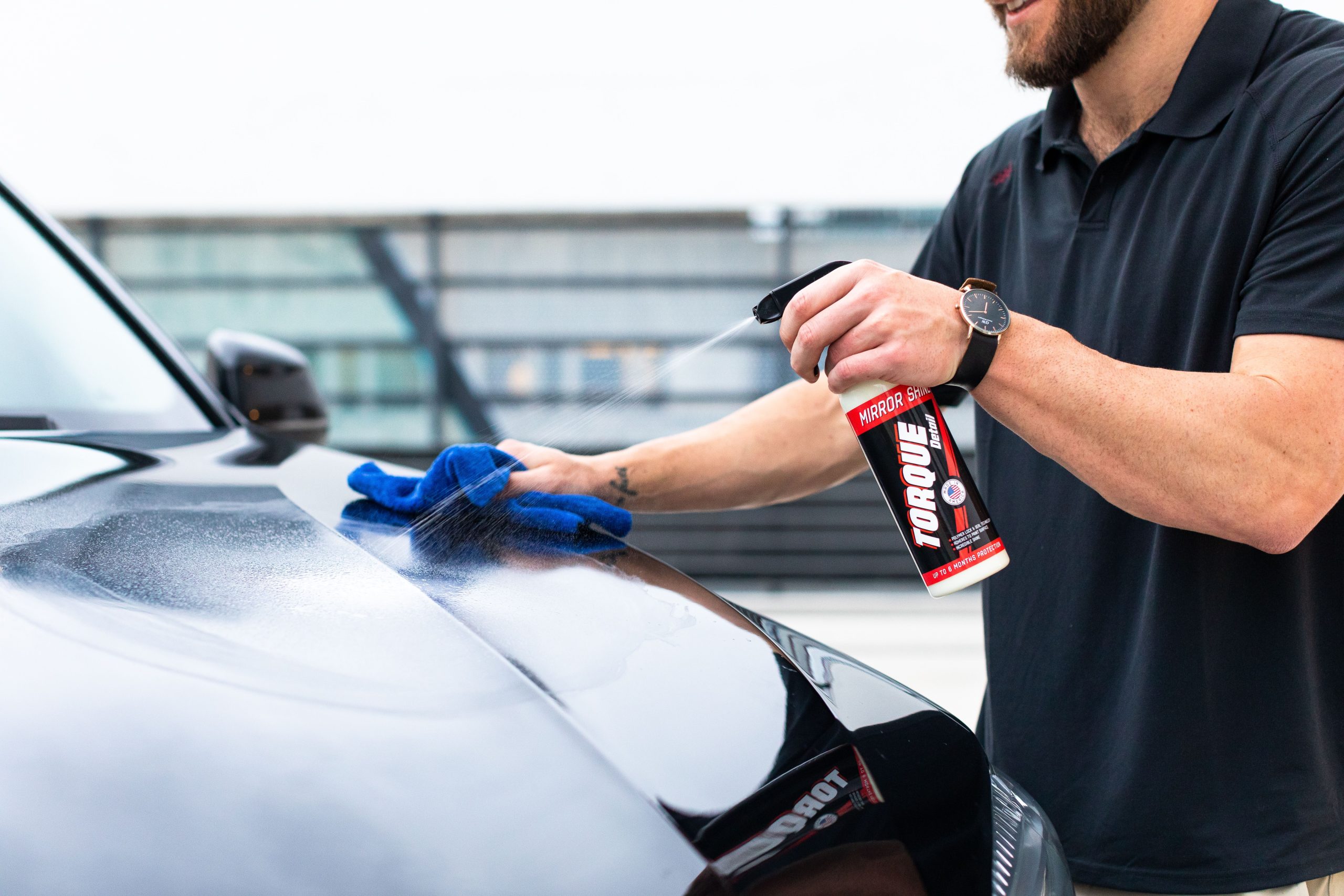 Close-up of hands cleaning a car surface with a microfiber cloth